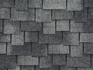 Picture with a textured background of asphalt shingles. Backdrop of grey roof shingles.